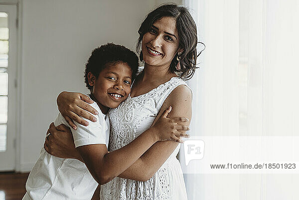 Mother and Son in natural-light studio hugging and smiling at camera