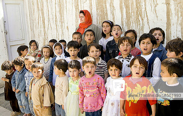 A teacher watches as children in a Kabul child care center start their day with anthems and songs.