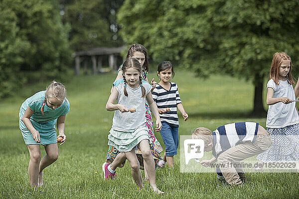 Group of children competing in an egg-and-spoon race in a park  Munich  Bavaria  Germany