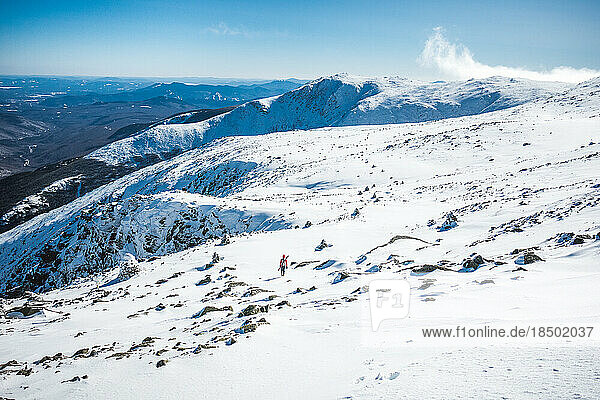 Ski mountaineer walking through frozen snow field on mountain