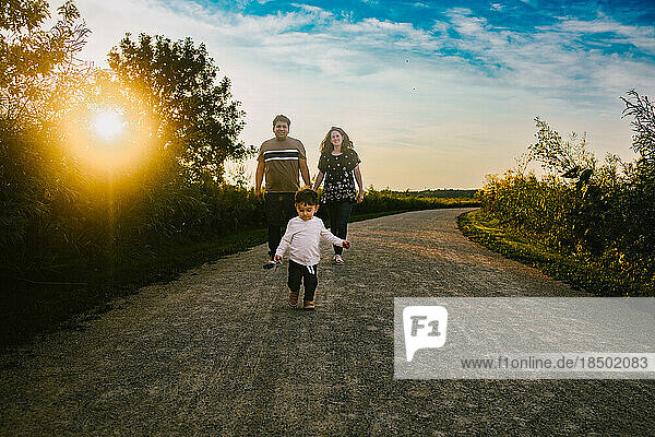 Family walks along a path in summer outside in nature and sunshine