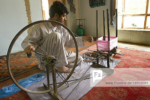Spinning silk thread on a spinning wheel.