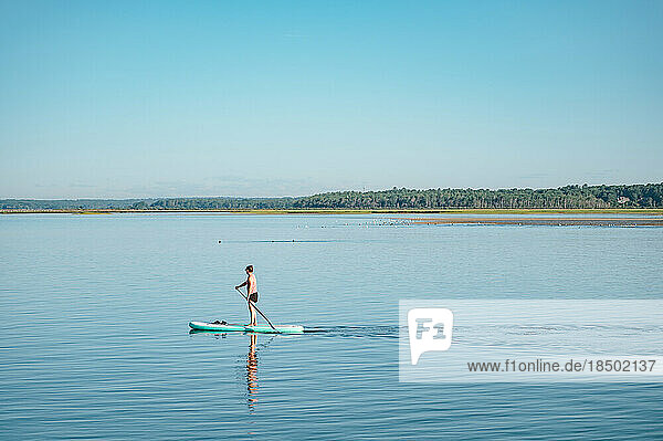 Woman on stand-up paddleboard on ocean in summer