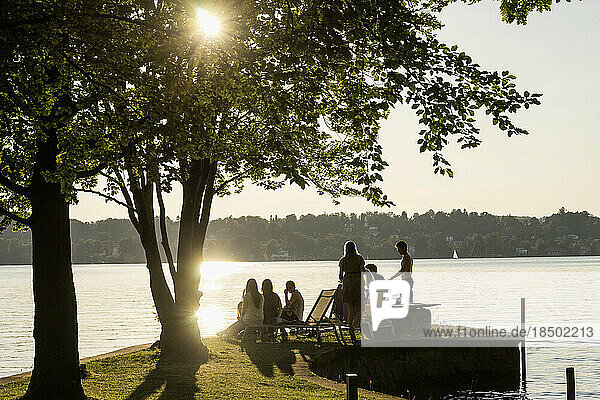Group of young friends partying at lakeside during sunset  Bavaria  Germany