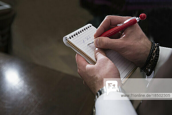 Cropped image of waiter writing order in note pad