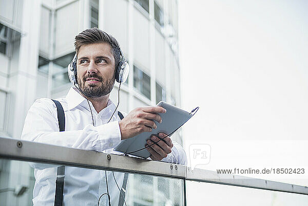 Businessman listening music with headphone in digital tablet  Munich  Bavaria  Germany