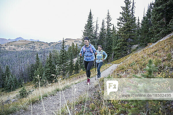 Two young women trail runners enjoy gentle uphill single track trail