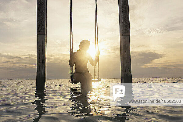 Woman sitting on rope swing at beach against sunset  Gili Trawangan  Lombok  Indonesia