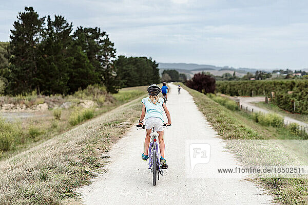 Tween girl riding a bicycle on a path in New Zealand