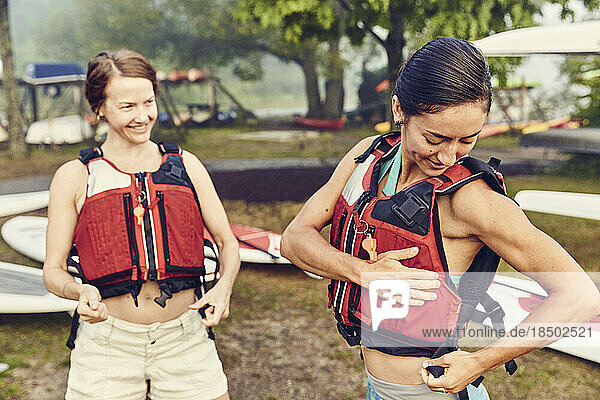 Young women put on their life jackets in preparation for kayak trip