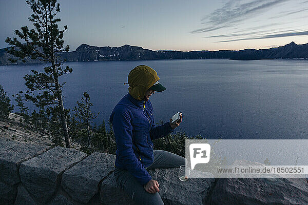 A woman takes a photo of Crater Lake National Park in Oregon.