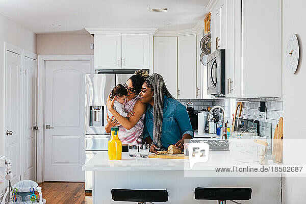 Mothers playing with son while preparing food in kitchen at home