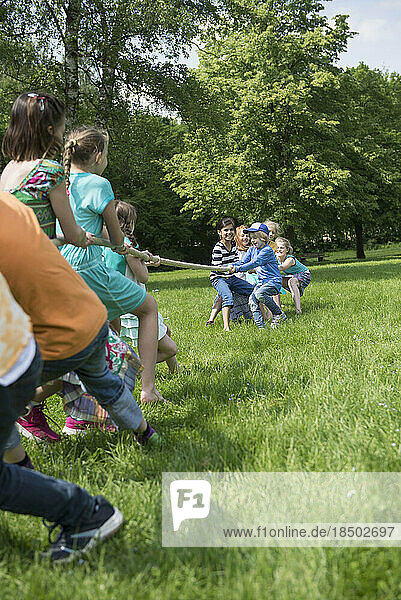 Group of children playing tug-of-war in a park  Munich  Bavaria  Germany