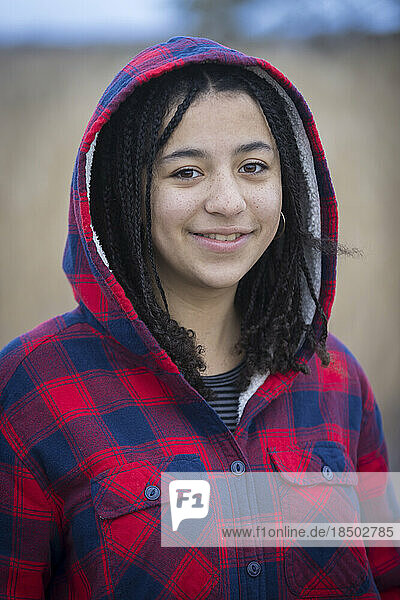 portrait of biracial young woman smiling with braids and hood