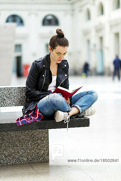 Young woman reading book  waiting at train station