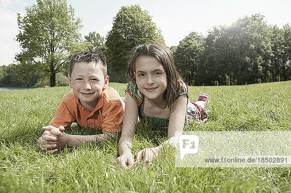 Two friends lying on grass in a park  Munich  Bavaria  Germany