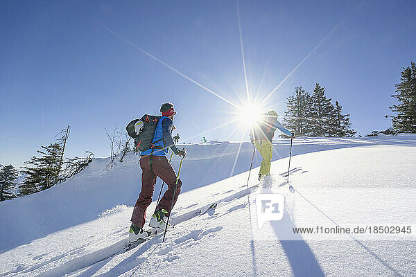 Skiers climbing snow mountain against sky