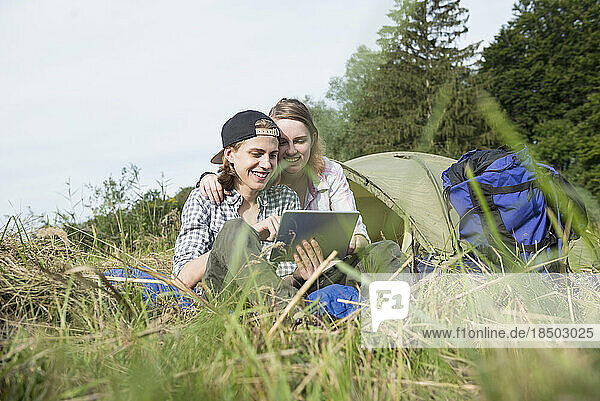 Young couple using digital tablet in front of camp tent  Bavaria  Germany