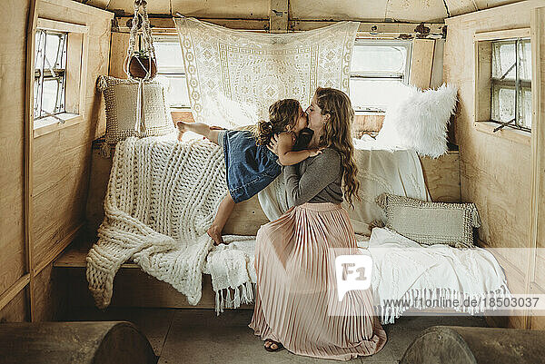 Mother and daughter kissing in boho studio setup