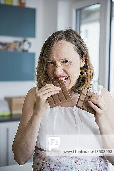 Portrait of a pregnant woman eating chocolates in the kitchen  Munich  Bavaria  Germany