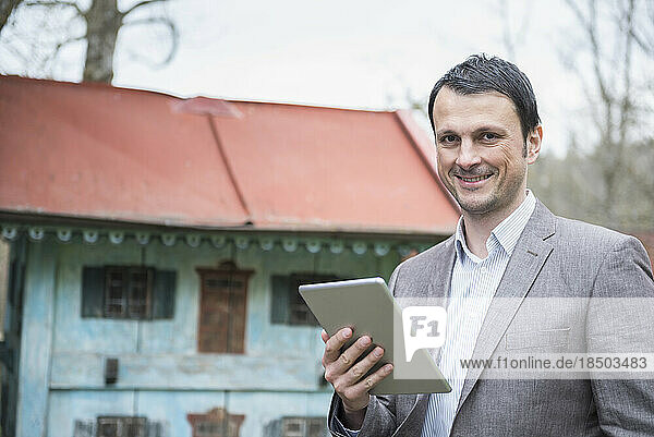 Portrait of a mature businessman using digital tablet outside and smiling  Bavaria  Germany