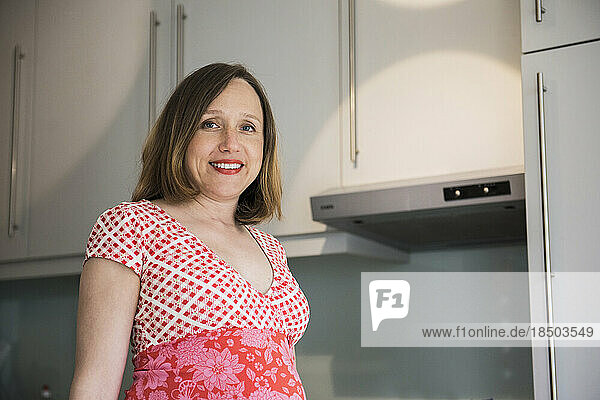 Portrait of a pregnant woman standing in the kitchen and smiling  Munich  Bavaria  Germany