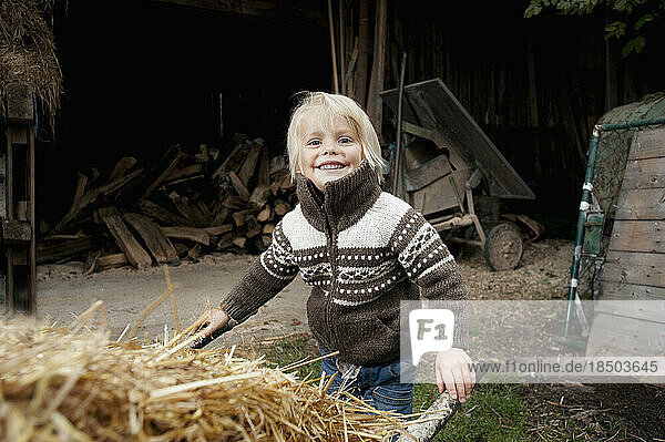 Portrait of a little boy pushing wheelbarrow in the farm  Bavaria  Germany