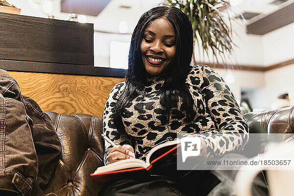 portrait of black woman in a coffee shop taking work notes