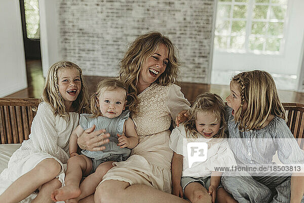 Mother and daughters laughing at each other on studio couch