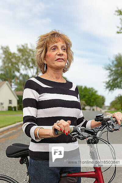 Mature woman in her seventies enjoying a day outside on her bike.