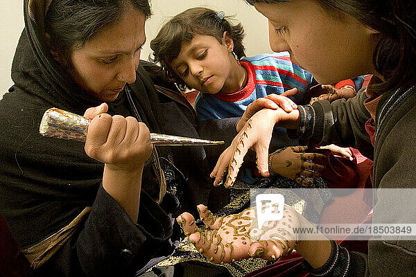 Woman puts henna on her daughters' hands in Kabul.