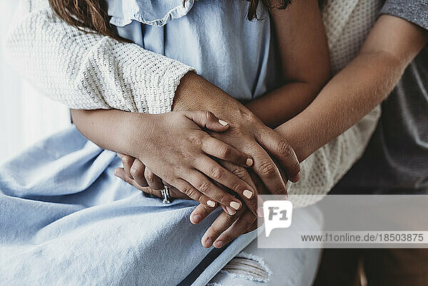 Close up of family's hands intertwined in studio