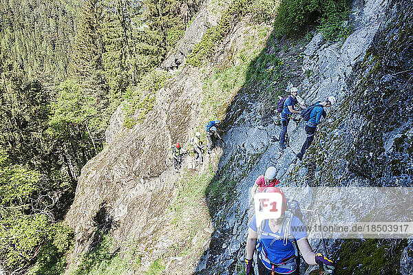 Group of people climbing steep rock face via ferrata towards Stuibenfall Waterfall  Otztal  Tyrol  Austria