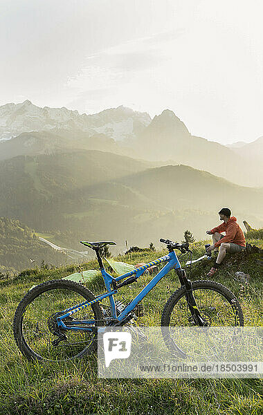 Mountain biker taking a break admiring scenic mountain view  Bavaria  Germany