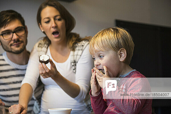 Little boy eating dessert with mouth wide open while parents are shocked  Munich  Germany