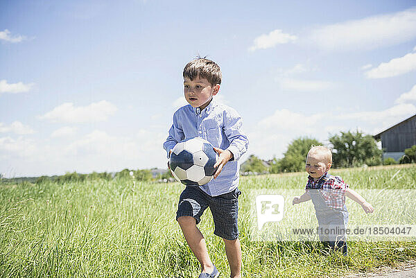 Small boy playing football with his brother on meadow in the countryside  Bavaria  Germany
