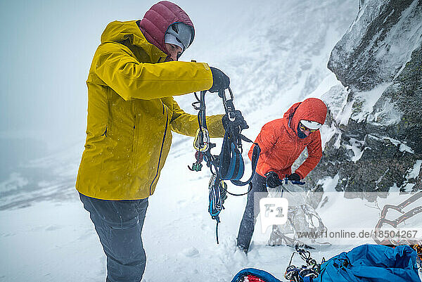 Male climbs putting equipment on for ice climb in snow