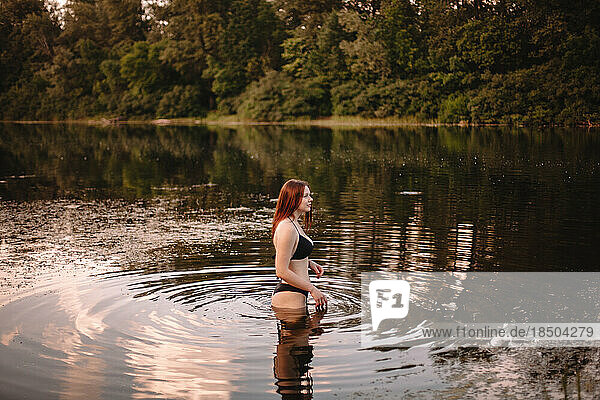 Young woman in a bikini standing in lake in forest