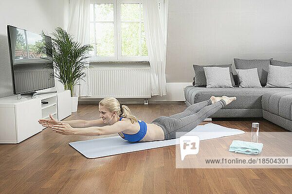 Young woman exercising on exercise mat in living room  Bavaria  Germany