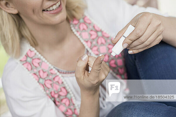 Close-up of woman squeezing tube of cream onto finger