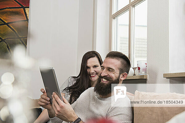 Couple watching digital tablet on sofa