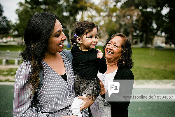 Mother holding daughter as grandmother looks on