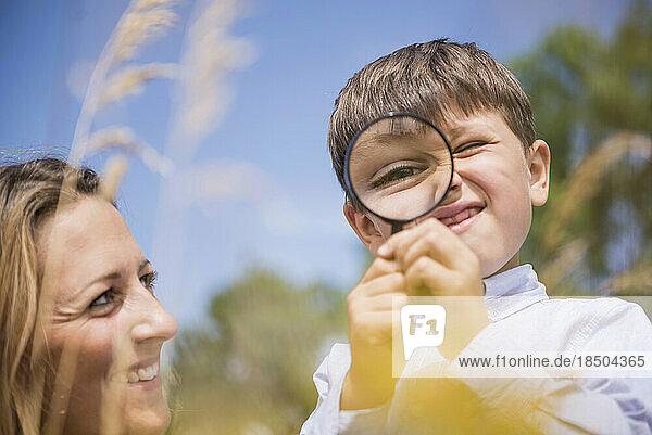 Little boy looking through magnifying glass with his mother in the countryside  Bavaria  Germany