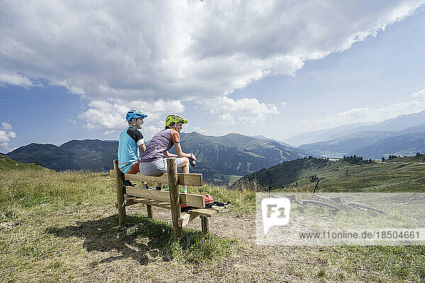 Young couple of mountainbikers sitting on bench in alpine landscape  Zillertal  Tyrol  Austria