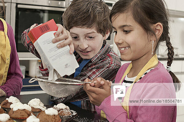 Students sprinkle powdered sugar on muffins in home economics class  Bavaria  Germany