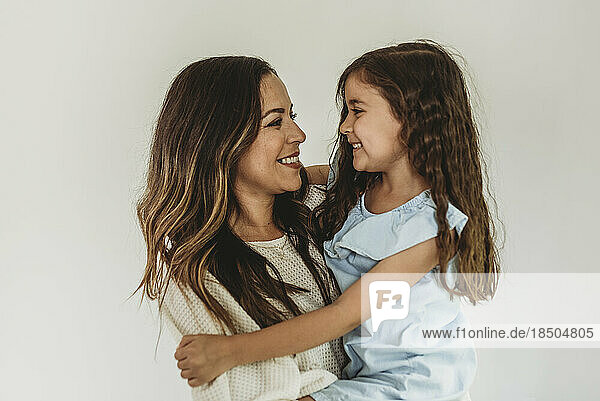 Mother and daughter looking at eachother and smiling in studio