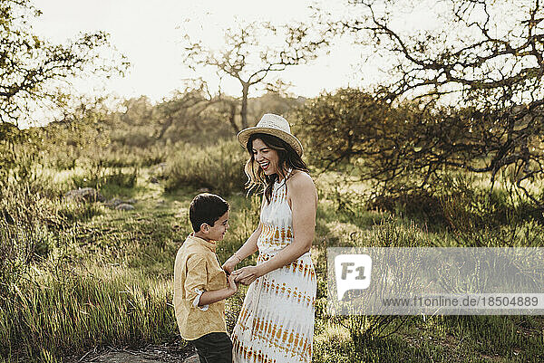 Side view of young mother and son playing in california meadow