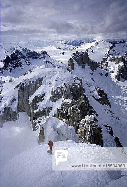A mountaineer crosses Cerro Torre's west ridge in blowing snow  with Cerro's Piergiorgio and Marconi in the background  Argentin