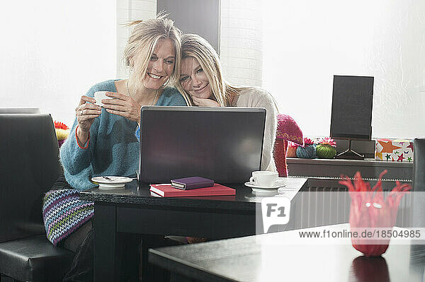 Two friends using laptop and drinking coffee in coffee shop  Bavaria  Germany