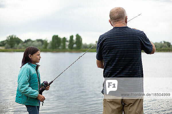 Grandfather helping granddaughter with her fishing pole